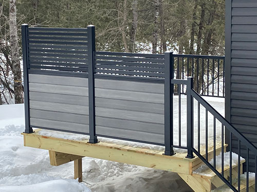 Une terrasse avec un mur d'intimité et des escaliers recouverts de neige.
