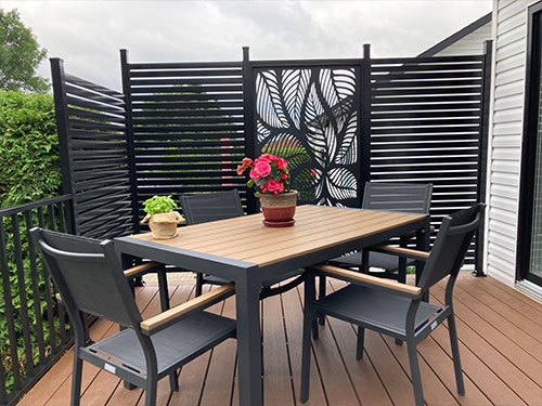 Une table et des chaises sur une terrasse, entourées d'un mur d'intimité.