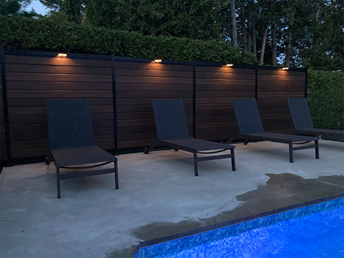 Une piscine entourée de chaises longues et illuminée par des lumières douces.