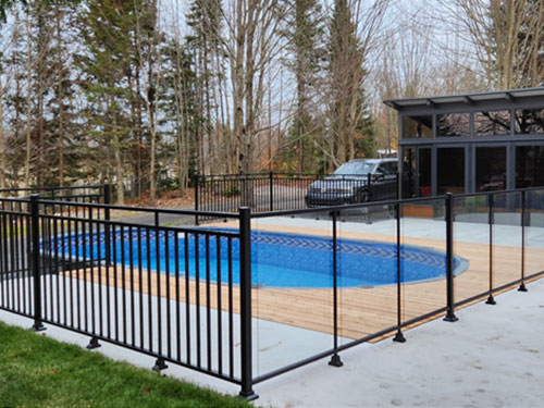 Une clôture de piscine noire entourant un deck en bois, offrant sécurité et esthétique.