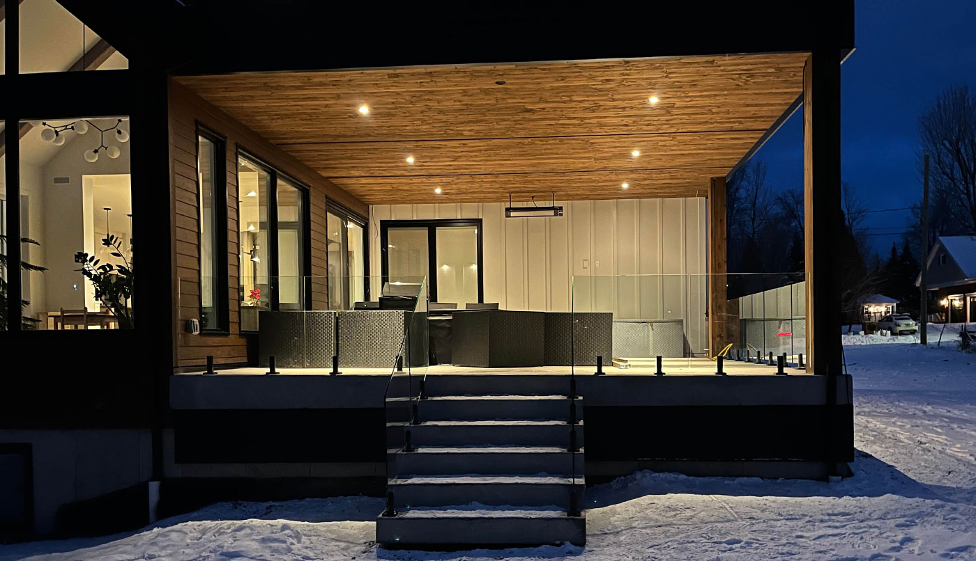 Résidence moderne dotée d'une terrasse et d'escaliers menant à l'entrée, dotée d'une clôture en panneaux de verre