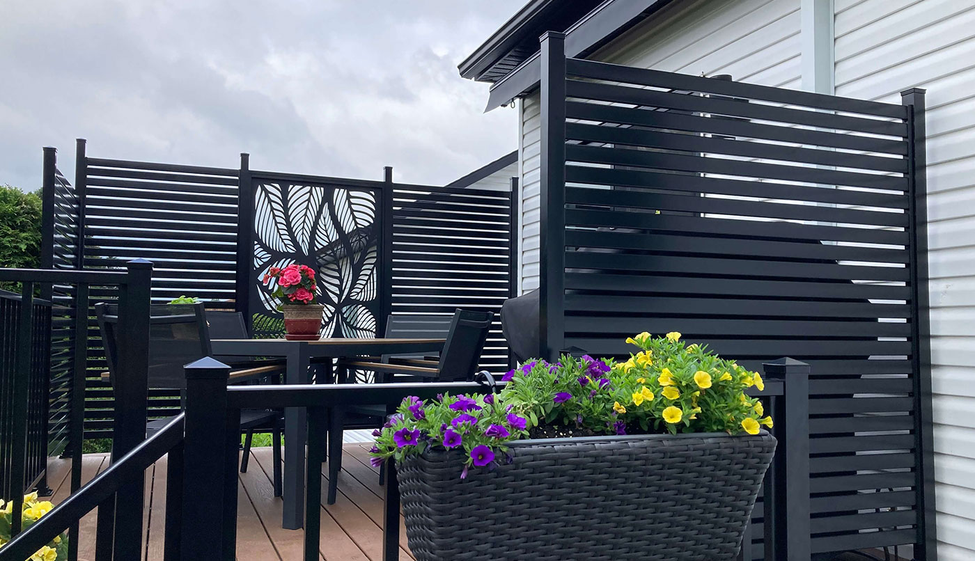 Une clôture en aluminium noire ornée d'un panier de fleurs colorées, ajoutant une touche de beauté à l'environnement.